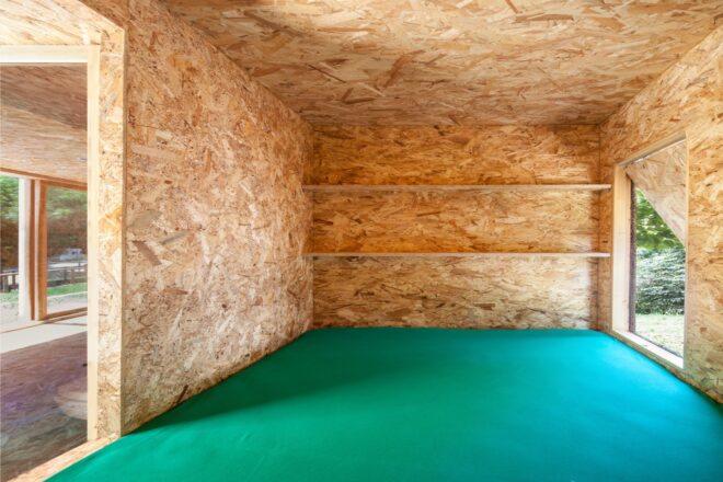 room clad entirely in plywood panels with green flooring