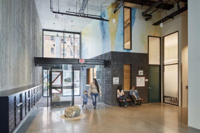 people walking through a lobby with dark brick walls and watercolor accents
