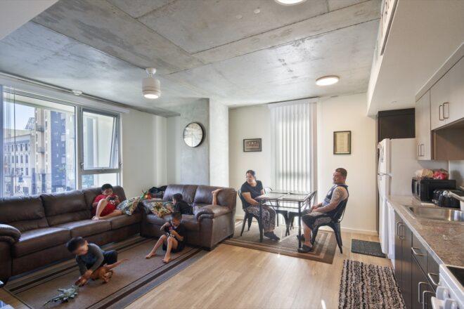 family relaxing on couches and at dining table in an apartment