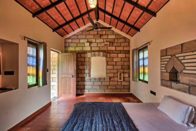 bed in large room with brick wall and gabled ceiling
