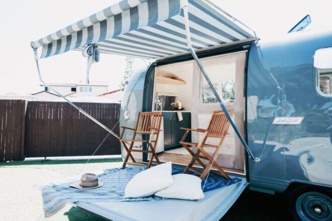 striped awning covering a fold-out deck with two wood chairs