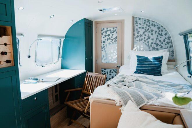 white bed beside a small white desk inside an Airstream