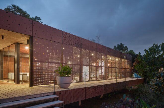 perforated weathered metal screen over wall of glass