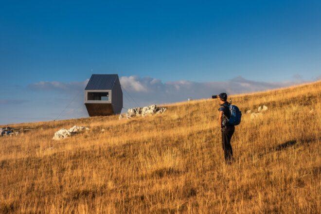 man walking towards a tiny bivouac in the distance