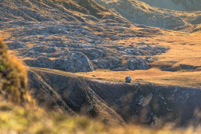large rugged landscape with tiny bivouac in the distance