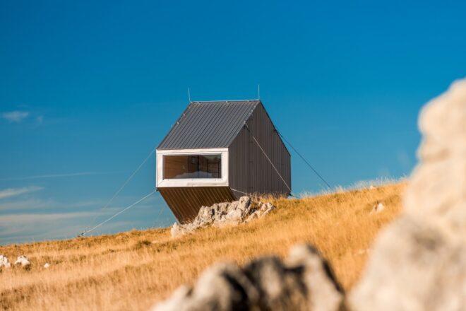 tiny angular structure on grassy landscape