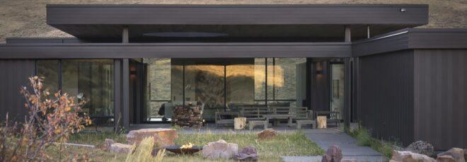 rocks and fire pit in central grassy courtyard near a dark home