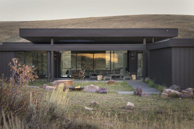 rocks and fire pit in central grassy courtyard near a dark home
