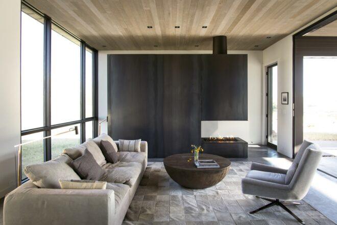 tan sofa and round wood coffee table near a large wood-framed fireplace