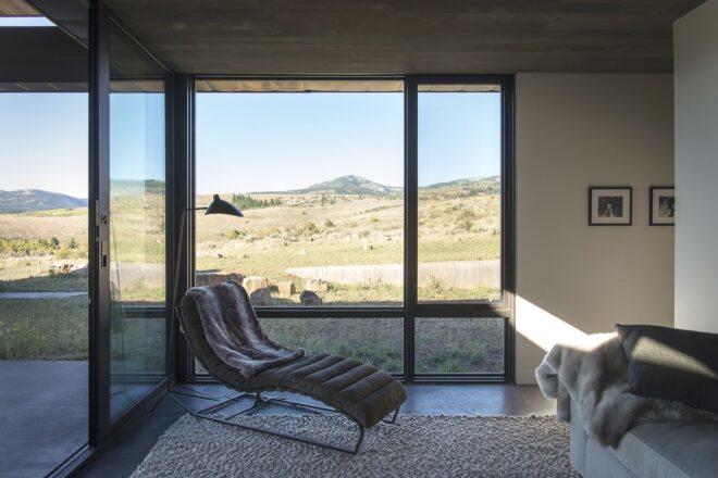 dark lounge chair beside massive window