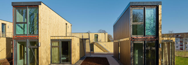 closeup of a line of shipping container micro-apartments covering in timber panels