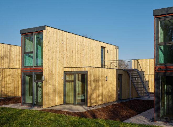 closeup of shipping container micro-apartments with windows and timber siding