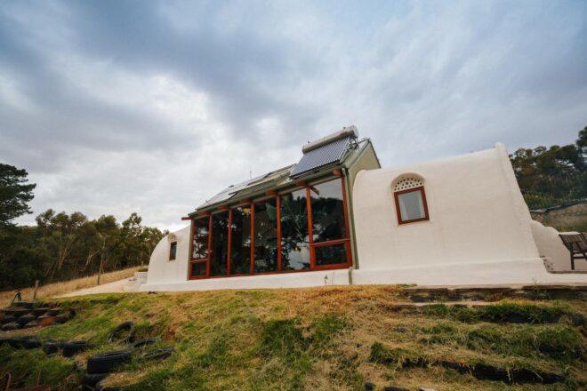 white earthship home with large glass windows