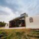 white earthship home with large glass windows