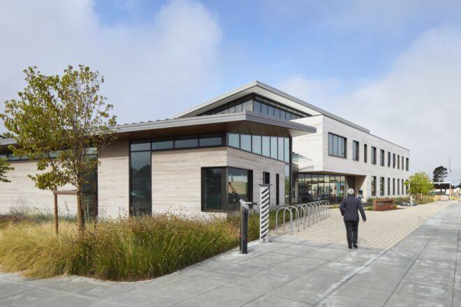 people walking to wood-clad library building with slanted roof