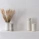 white water bottle and coffee cup next to tan vase and white vase full of wheat