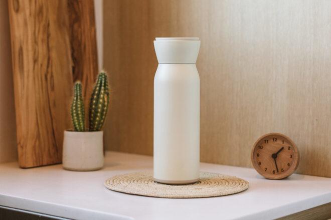 white reusable water bottle on a counter near wood cutting boards and a small plant