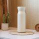white reusable water bottle on a counter near wood cutting boards and a small plant
