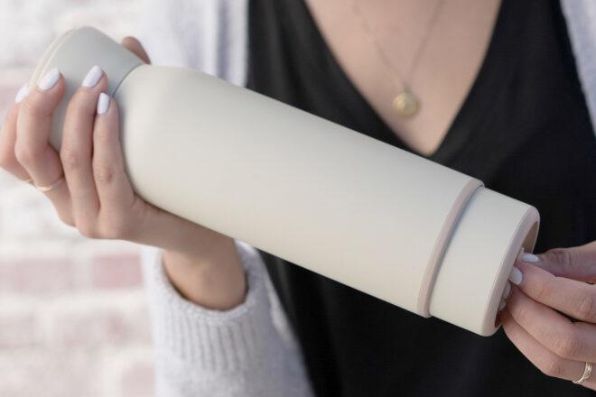 person removing white coffee cup from a white reusable water bottle