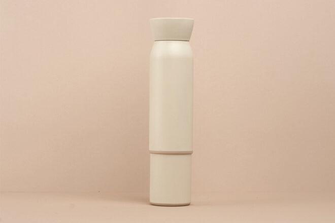 white reusable water bottle stacked on top of a small white coffee cup