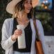 person carrying white reusable water bottle while on a walk