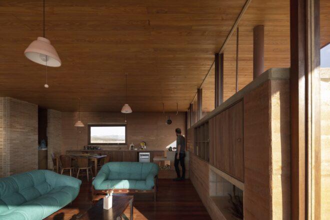 long rammed earth wall across from two teal sofas