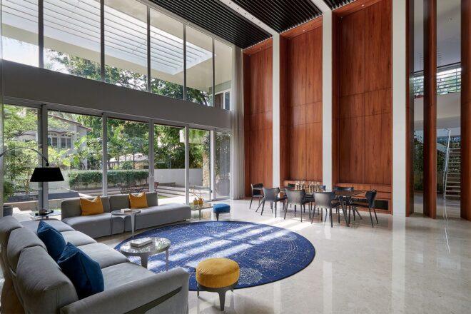 large interior living space with triple-height ceiling, gray sectional sofa and round blue rug