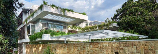 large stone wall around white home with hanging plants on the roof