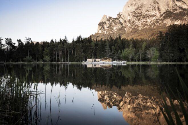 a lake with forest and mountains in the background and reflected in the lake