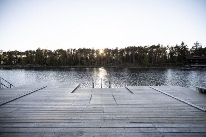 a wood dock overlooking a lake with trees in the background