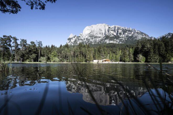 a lake with forest and mountains in the background and reflected in the lake