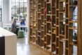 a tall, avant-garde brown bookcase. in the background, two people sit at a table together