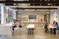 a clean, industrial style kitchen area within the studio building. people sit and have lunch