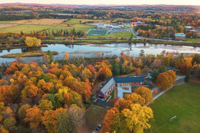 aerial view of V-shaped brick building near red, orange and yellow trees