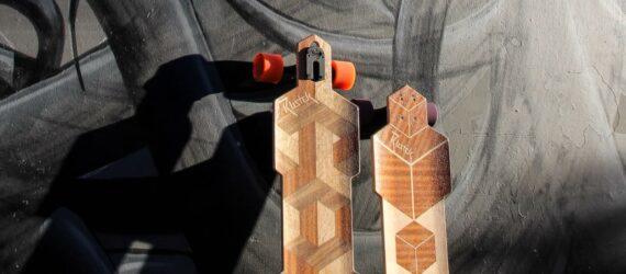 two wooden skateboards up against a grey and black wall