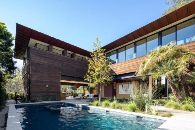 a home with a wood facade surrounds a swimming pool
