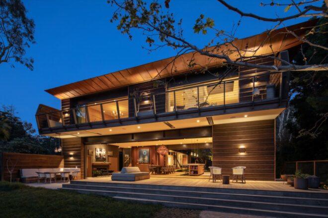 the exterior of a wood-sided home lit up from the inside at night