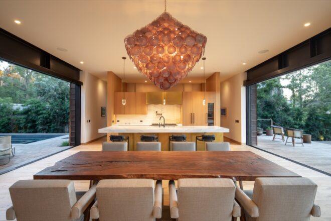 a large statement lamp hangs from the ceiling over a wood dining table with white chairs
