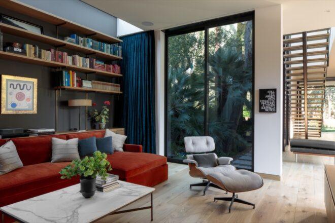 a living area with bookshelves and a sliding glass door that shows the woods outside