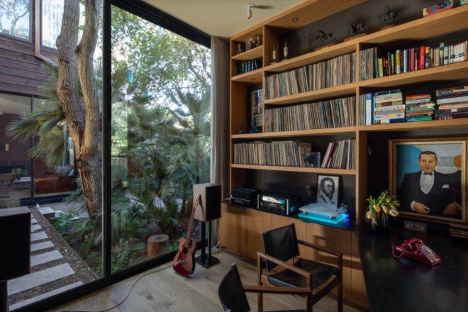 a floor-to-ceiling bookshelf in a study room, with a sliding glass door that showcases the woods outside