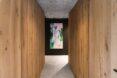 a hallway with light-colored wood walls and art featured on the opposite wall