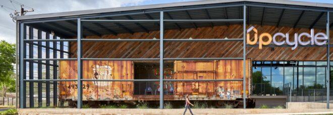 weathered steel building with gabled roof and sign that says, "Upcycle"