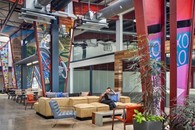 tan sofas in double-height office building with painted support beams