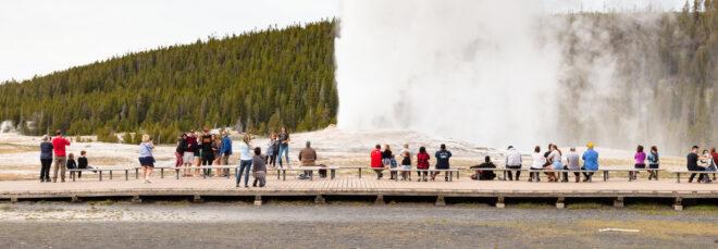 crowd of people watching geyser erupt at Yellowstone National Park