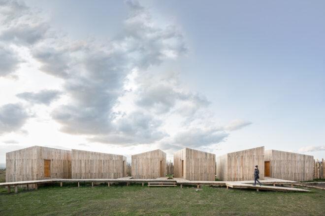 wood cabins with slanted roofs connected by winding wooden walkway