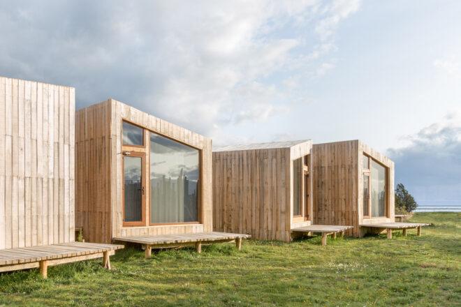 wood cabins with slanted roofs and end walls made of glass