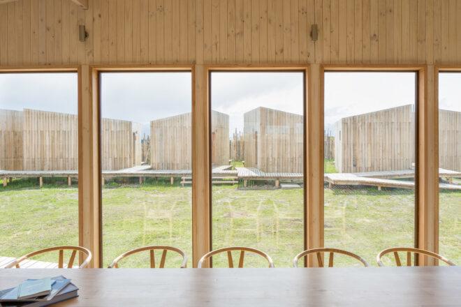 wood dining table and chairs facing wall of vertical windows