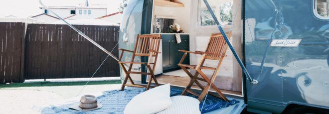 striped awning covering a fold-out deck with two wood chairs