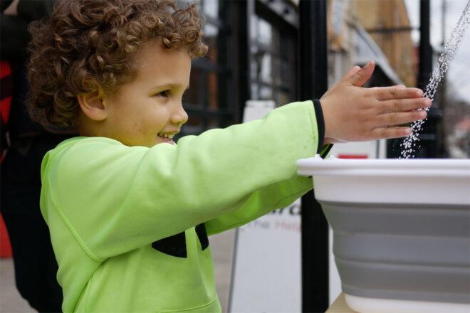 child washing hands in portable sink
