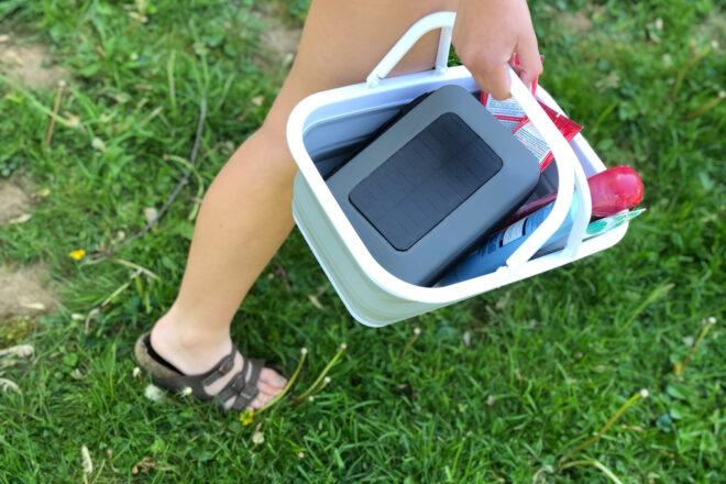 person carrying snacks and a solar charger in a portable, basket-like sink
